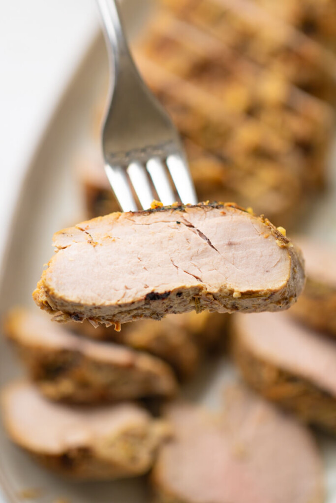 Sliced rosemary garlic pork tenderloin on fork.