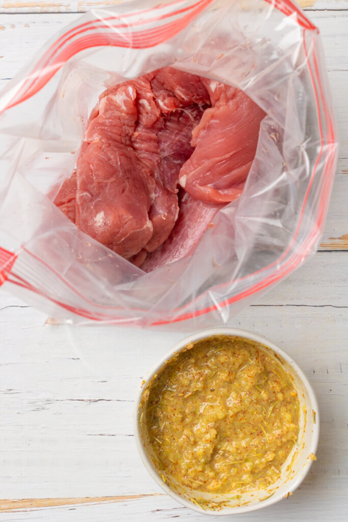 Pork tenderloin in ziplock bag and bowl of marinade in front of it.