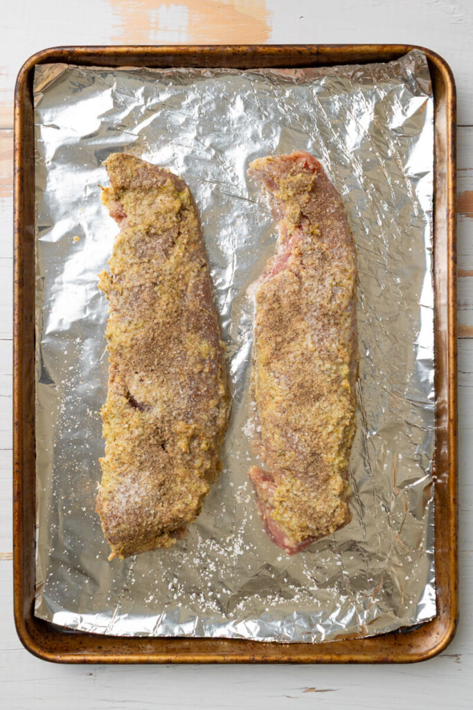 Marinated rosemary garlic pork tenderloins on baking sheet lined with aluminum foil.