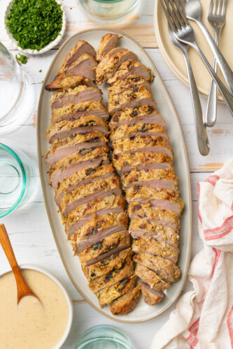 Cooked rosemary garlic pork tenderloin sliced on plate.