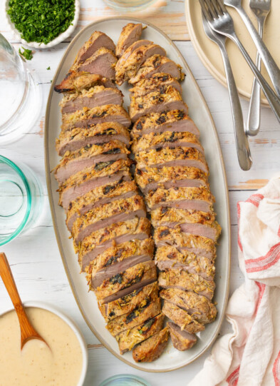 Cooked rosemary garlic pork tenderloin sliced on plate.