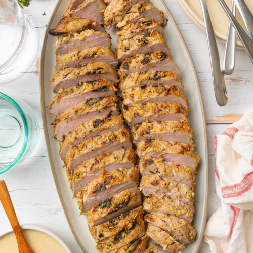 Cooked rosemary garlic pork tenderloin sliced on plate.
