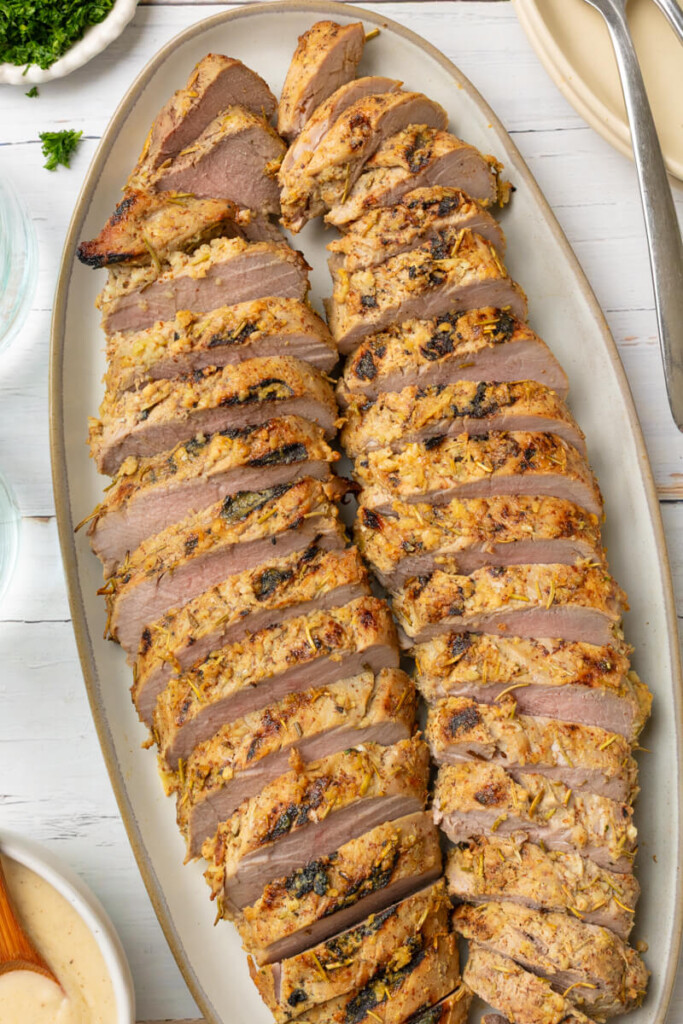 Cooked rosemary pork tenderloin sliced on plate.