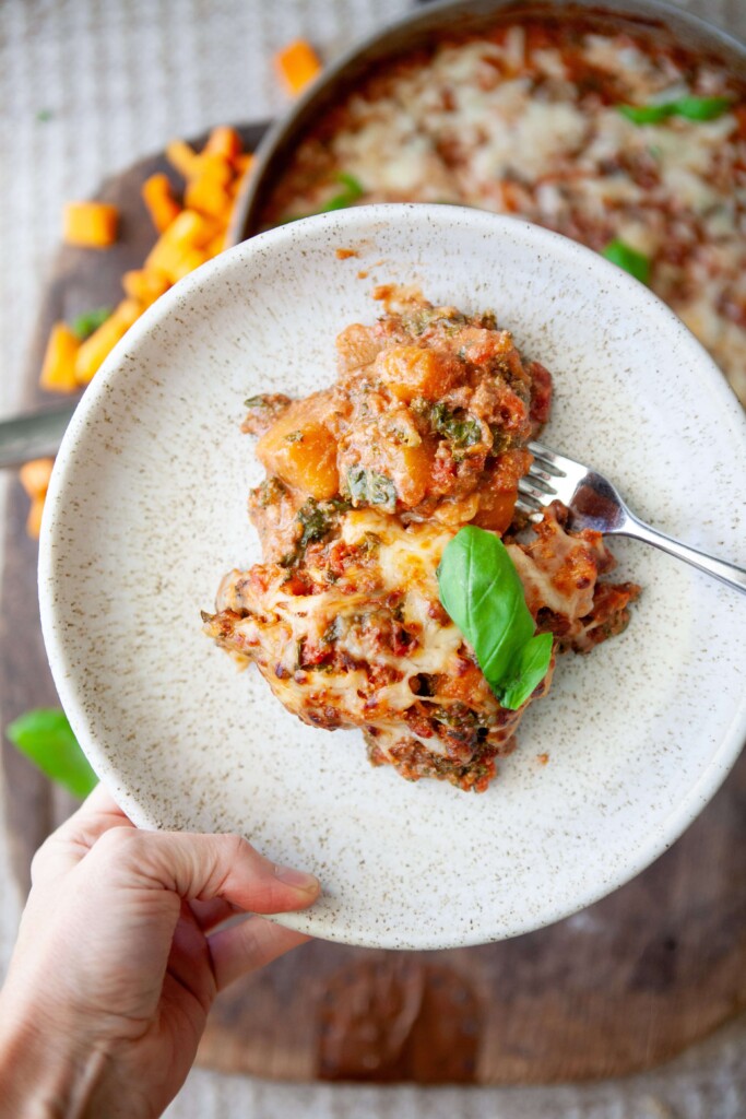Creamy tomato butternut lasagna in bowl with fork.