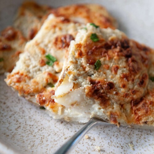 Stack of healthy scalloped potatoes on cream plate with fork.