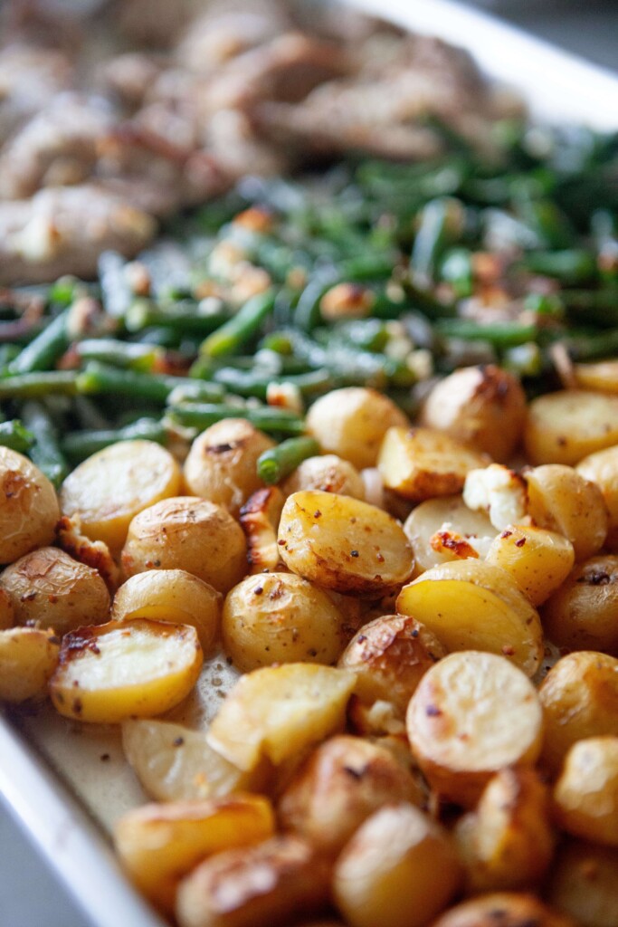 Potatoes, green beans and chicken thighs on large sheet pan.