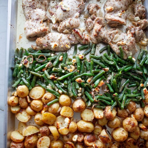 Chicken thighs, green beans and potatoes on sheet pan for lemon dijon chicken recipe.