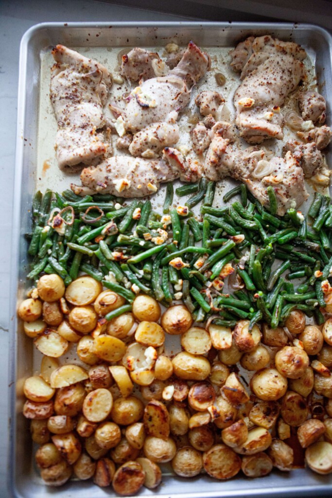Chicken thighs, green beans and potatoes on sheet pan for lemon dijon chicken recipe.