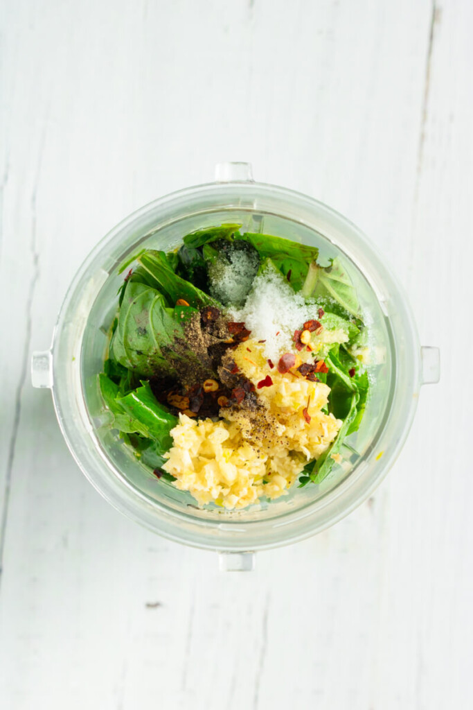 Adding ingredients for chimichurri in small blender cup.