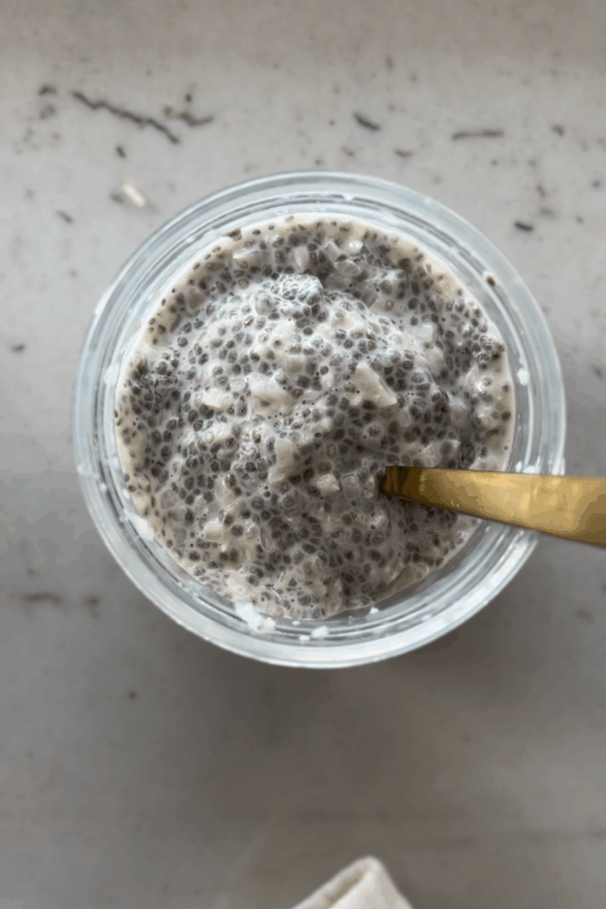 Cauliflower chia pudding in glass jar with gold spoon.