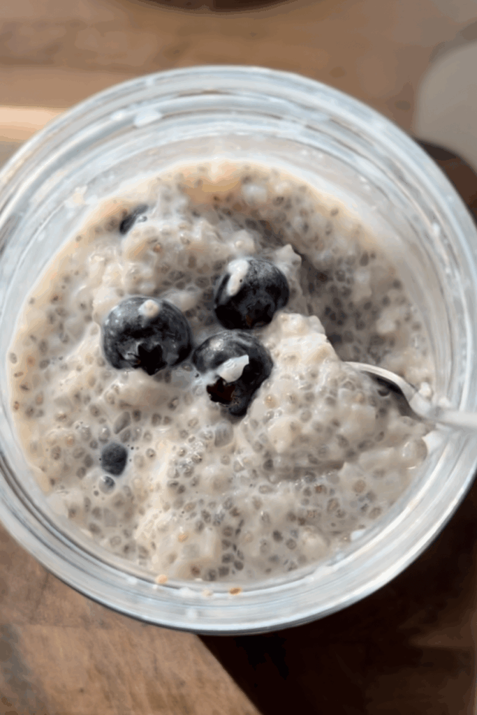 Cauliflower chia pudding in glass jar topped with blueberries with spoon.