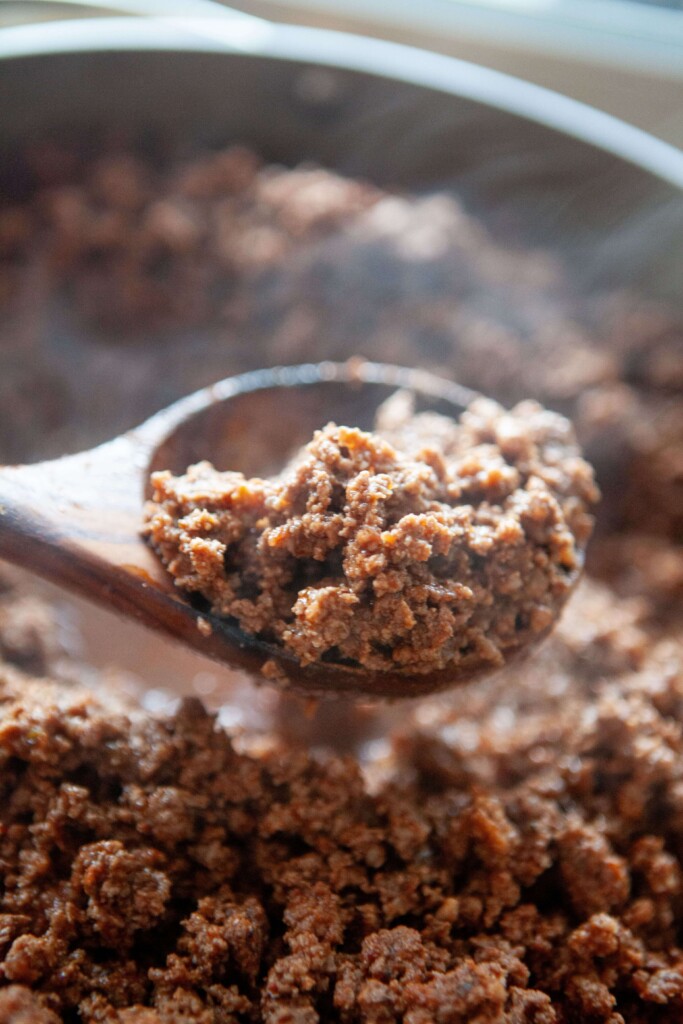 Cooked taco meat on wooden spoon.