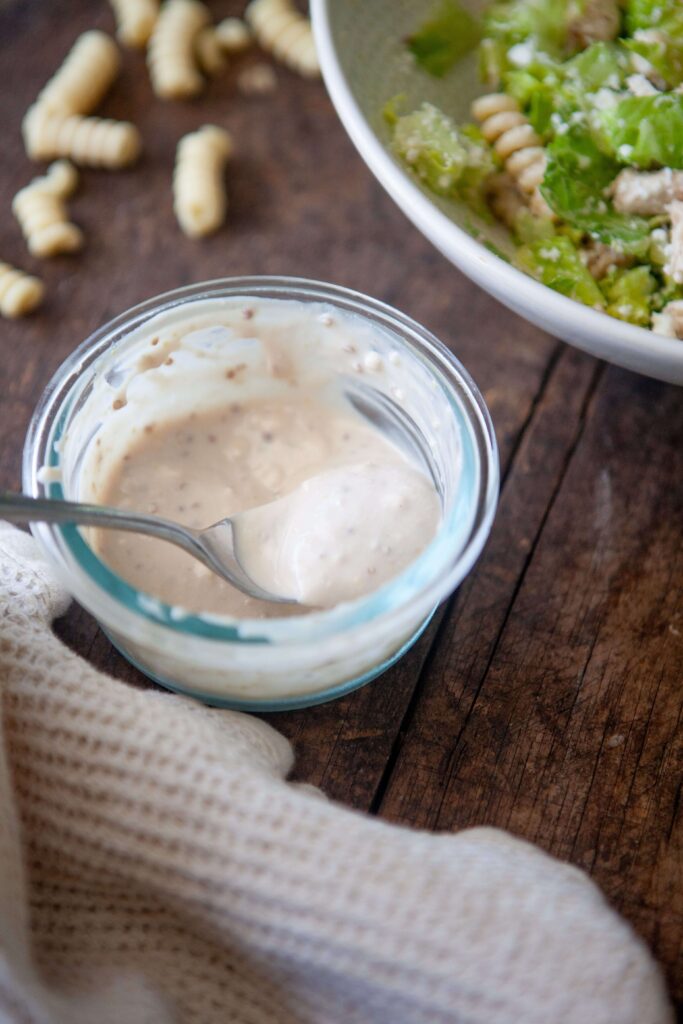 Greek yogurt caesar dressing in small glass bowl with spoon.