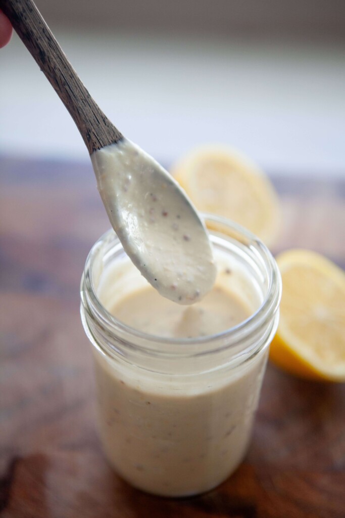 Wooden spoon and mason jar with greek yogurt caesar dressing.