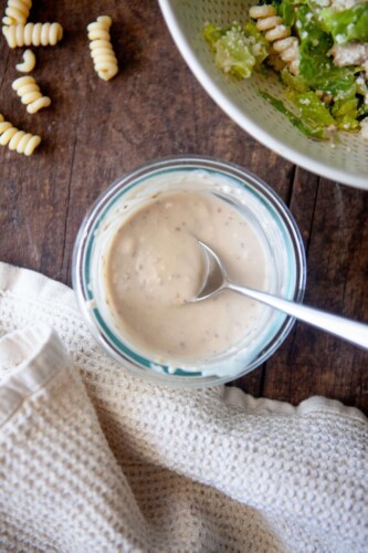 Greek yogurt caesar dressing in small glass bowl with spoon.