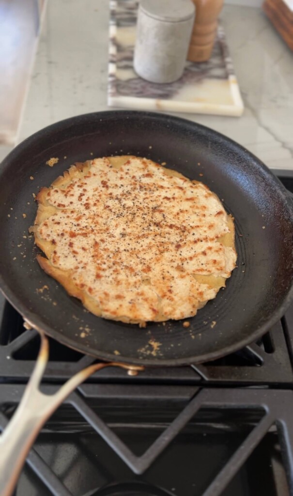 Egg wrap with ground chicken cooked on top for the base of a caesar salad ground chicken pizza.