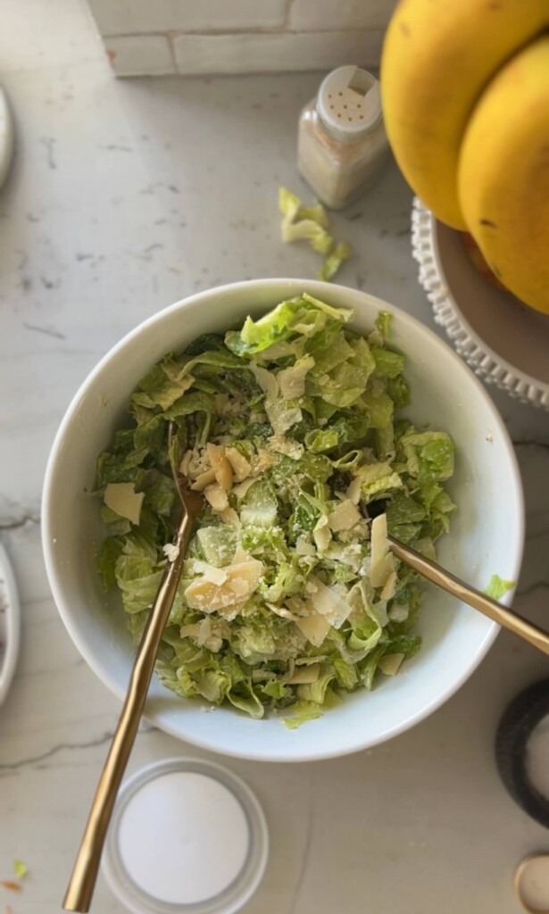 Mixing caesar salad together in large bowl for caesar salad ground chicken pizzas.