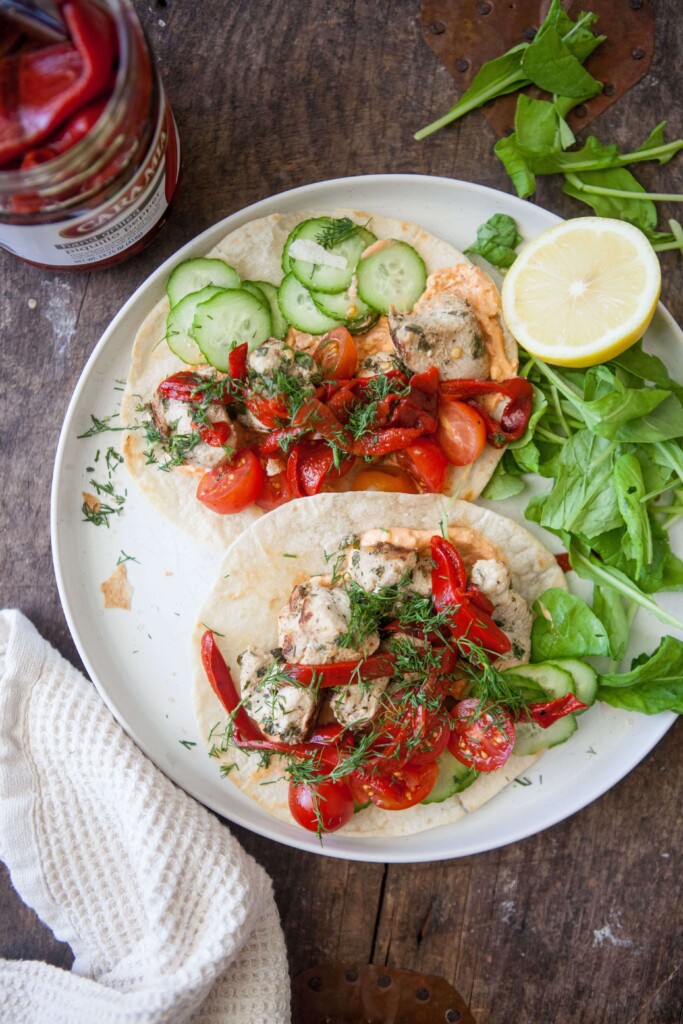 Harissa chicken feta wraps on white plate garnished with greens and lemon wedge.