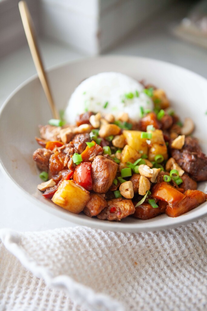 Pineapple chicken stir fry in bowl with rice in bowl.