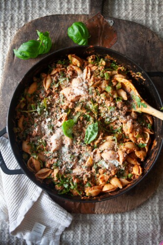 Ground beef and veggie pasta in cast iron skillet with wood spoon.