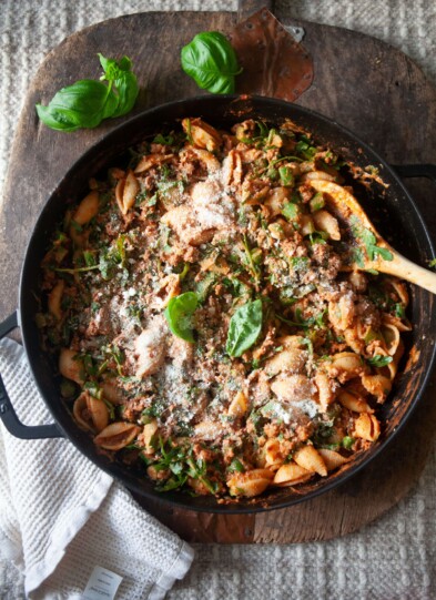 Ground beef and veggie pasta in cast iron skillet with wood spoon.