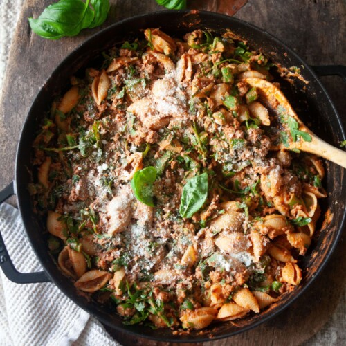Ground beef and veggie pasta in cast iron skillet with wood spoon.