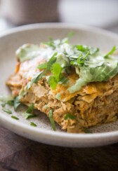 Instant pot chicken enchilada casserole topped with cilantro, avocado and cilantro ranch on plate.