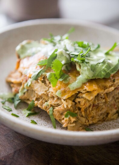 Instant pot chicken enchilada casserole topped with cilantro, avocado and cilantro ranch on plate.