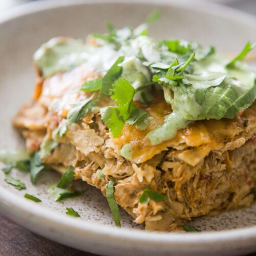 Instant pot chicken enchilada casserole topped with cilantro, avocado and cilantro ranch on plate.