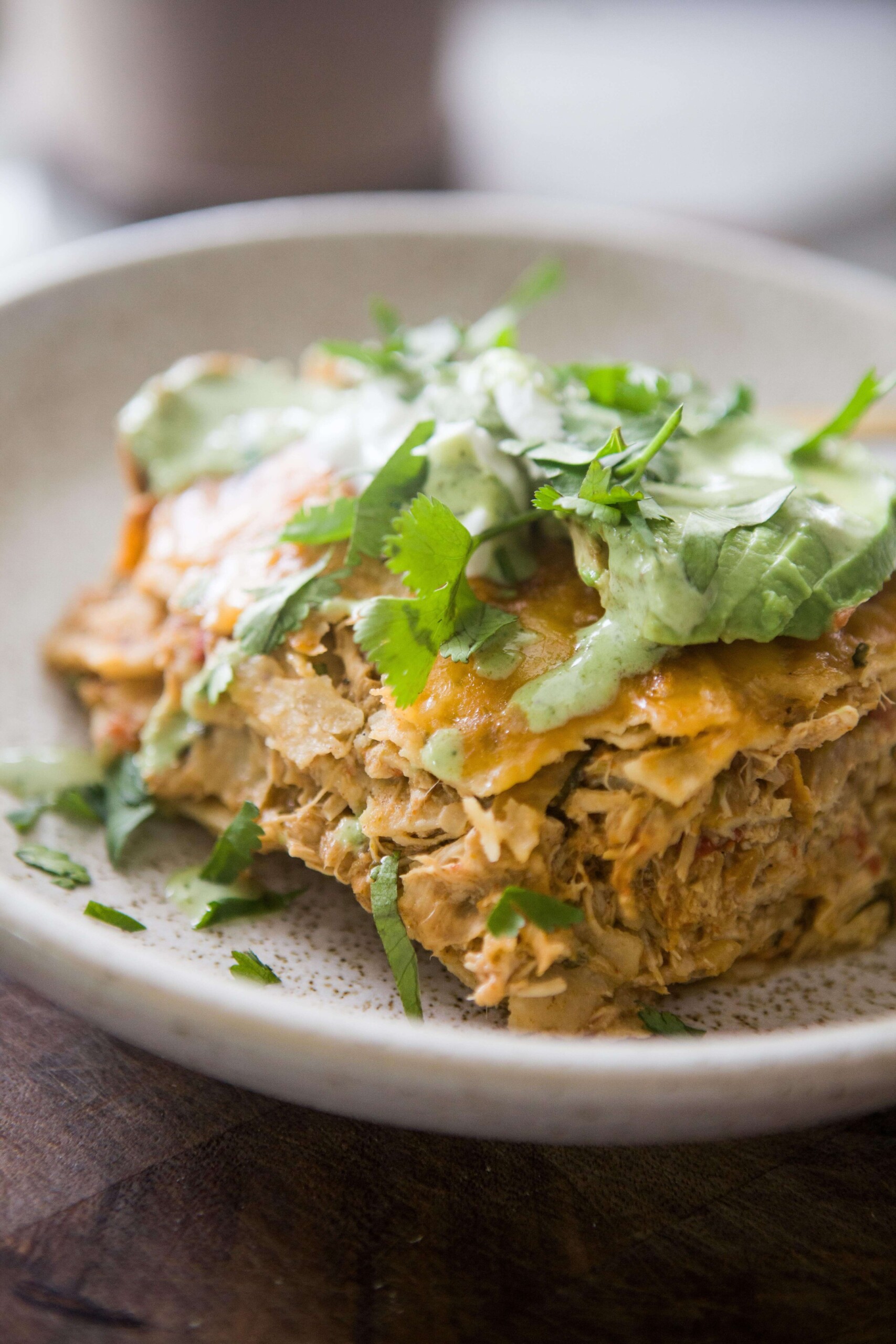 Instant pot chicken enchilada casserole topped with cilantro, avocado and cilantro ranch on plate.