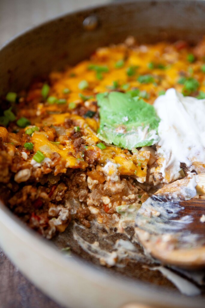 Skillet mexican potatoes in large pan topped with sour cream and avocado.