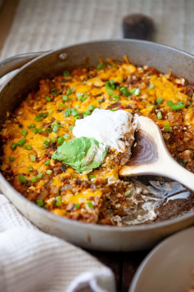 Mexican skillet potatoes with half of the portion scooped out of large skillet with wood spoon.
