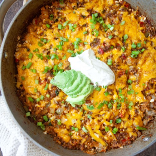 Skillet mexican potatoes cooked in a large skillet and topped with sour cream and avocado.