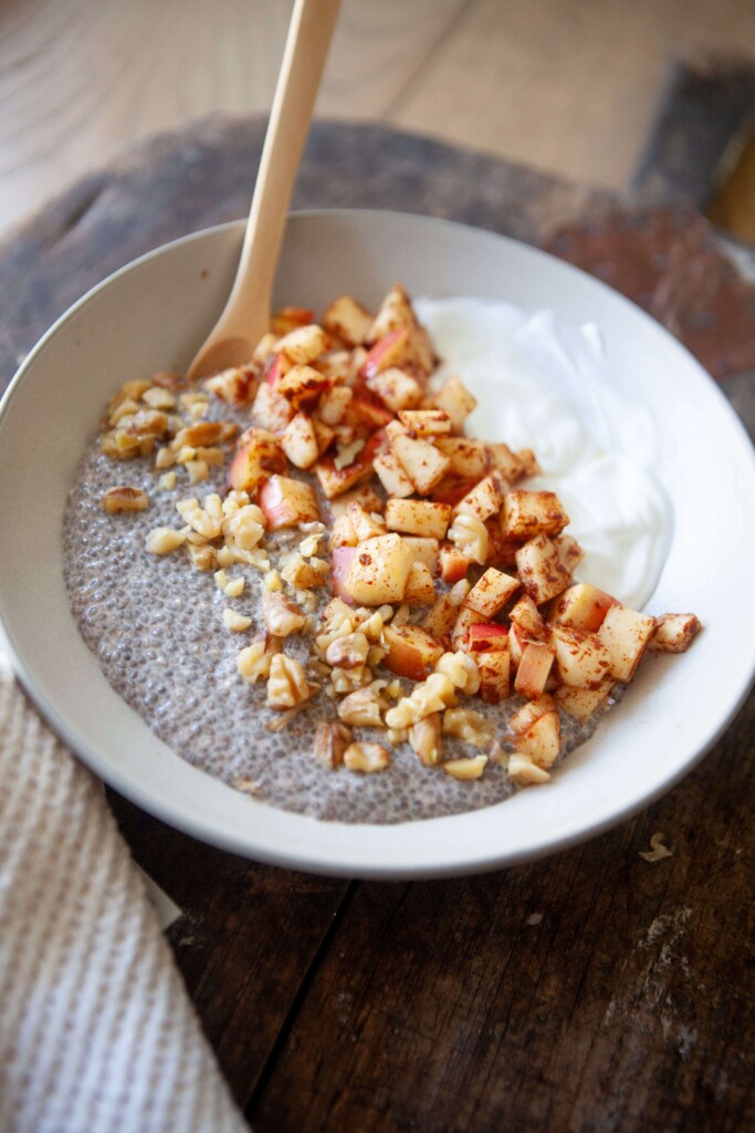 Apples, cinnamon, greek yogurt and chia pudding in bowl with spoon.