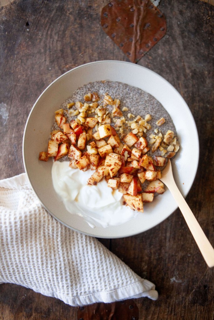 Apple cinnamon protein chia pudding in a bowl on table with spoon.