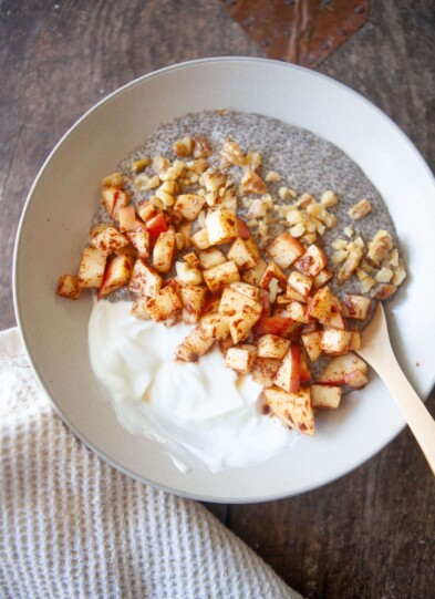 Apples, greek yogurt and chia pudding in a bowl with spoon.