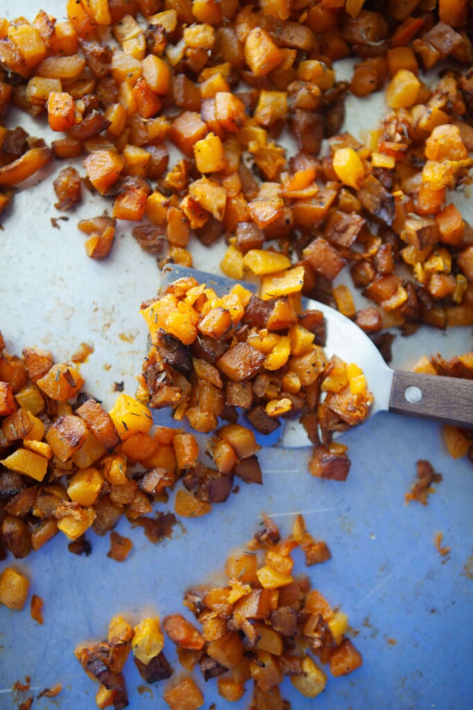 Roasted butternut squash cubes on pan with spatula.