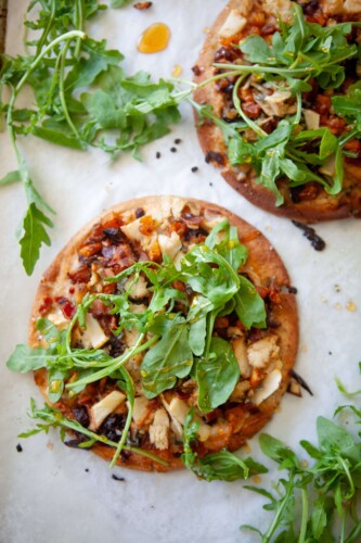 Two butternut squash, bacon, and caramelized onion flatbreads on a baking sheet.