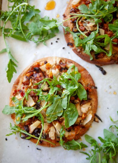 Two butternut squash, bacon, and caramelized onion flatbreads on a baking sheet.