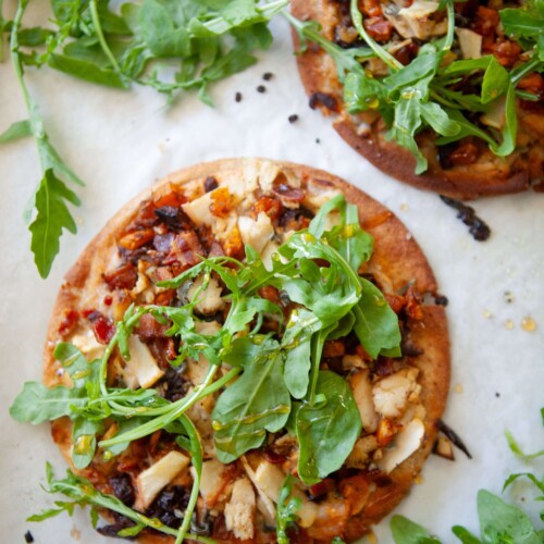 Two butternut squash, bacon, and caramelized onion flatbreads on a baking sheet.