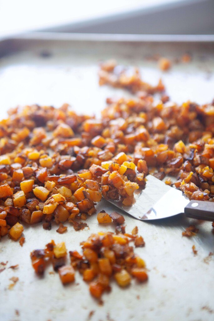 Butternut squash cubes roasted on baking sheet.