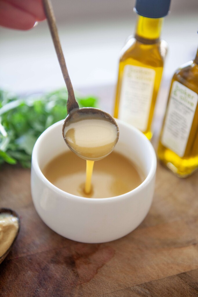 Sweet mustard vinaigrette in small bowl with gold spoon.