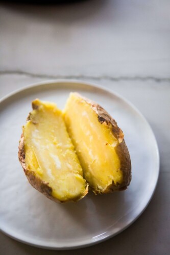 White sweet potato baked and cut in half on white plate.