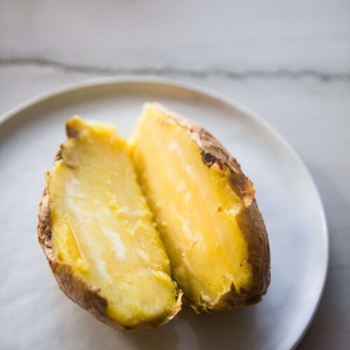 White sweet potato baked and cut in half on white plate.
