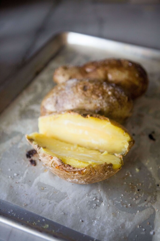 White sweet potato cut in half and open on parchment lined baking sheet.