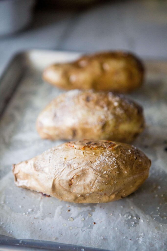 White sweet potato cut in half and placed on top of parchment lined baking sheet.