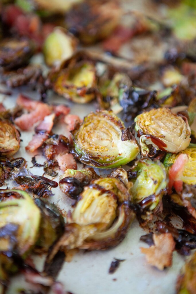 Upclose of roasted brussels and bacon on sheet pan.