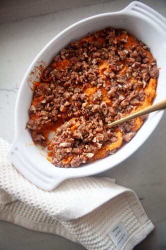 Healthier sweet potato casserole in baking dish with gold spoon.