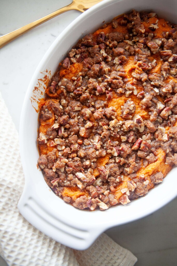 Healthier sweet potato casserole in white baking dish with gold spoon on side.