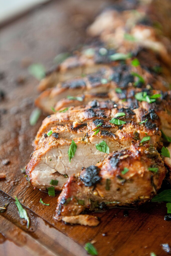 Balsamic, garlic and herb pork tenderloin sliced on cutting board.